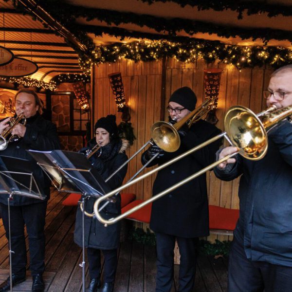 Eine kleine Blaskapelle bespielt die Besucherinnen und Besucher des Weihnachtsdorfes